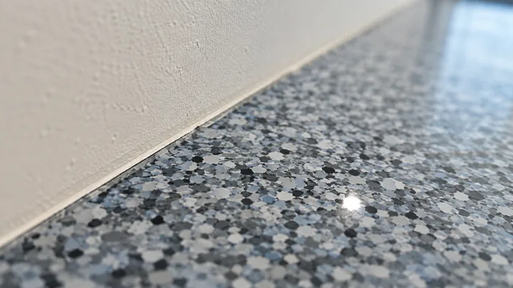 Dense gray-blue flake epoxy garage floor meeting a cleanly taped wall edge